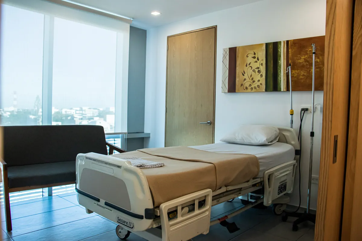 Private patient room with a hospital bed and a large window at Mayan Medical Group