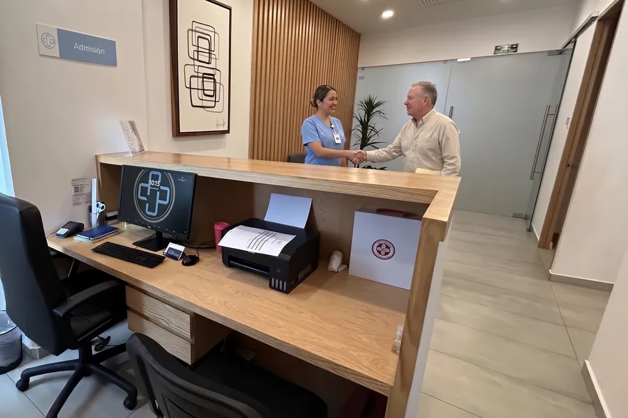 A receptionist welcoming a patient at the clinic's front desk in Cancún